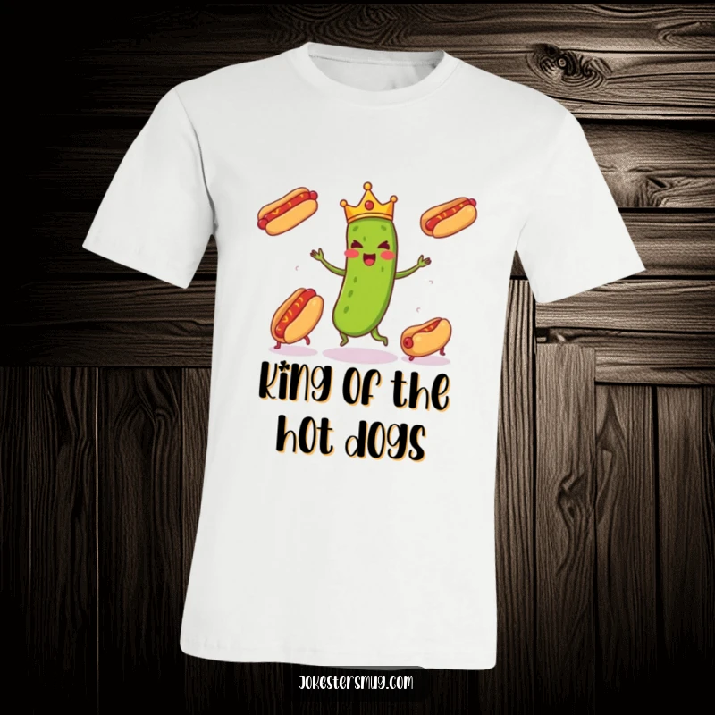Funny pickle wearing a tiny crown enthusiastically juggling three runaway hot dogs, a humorous scene on this funny t-shirt.